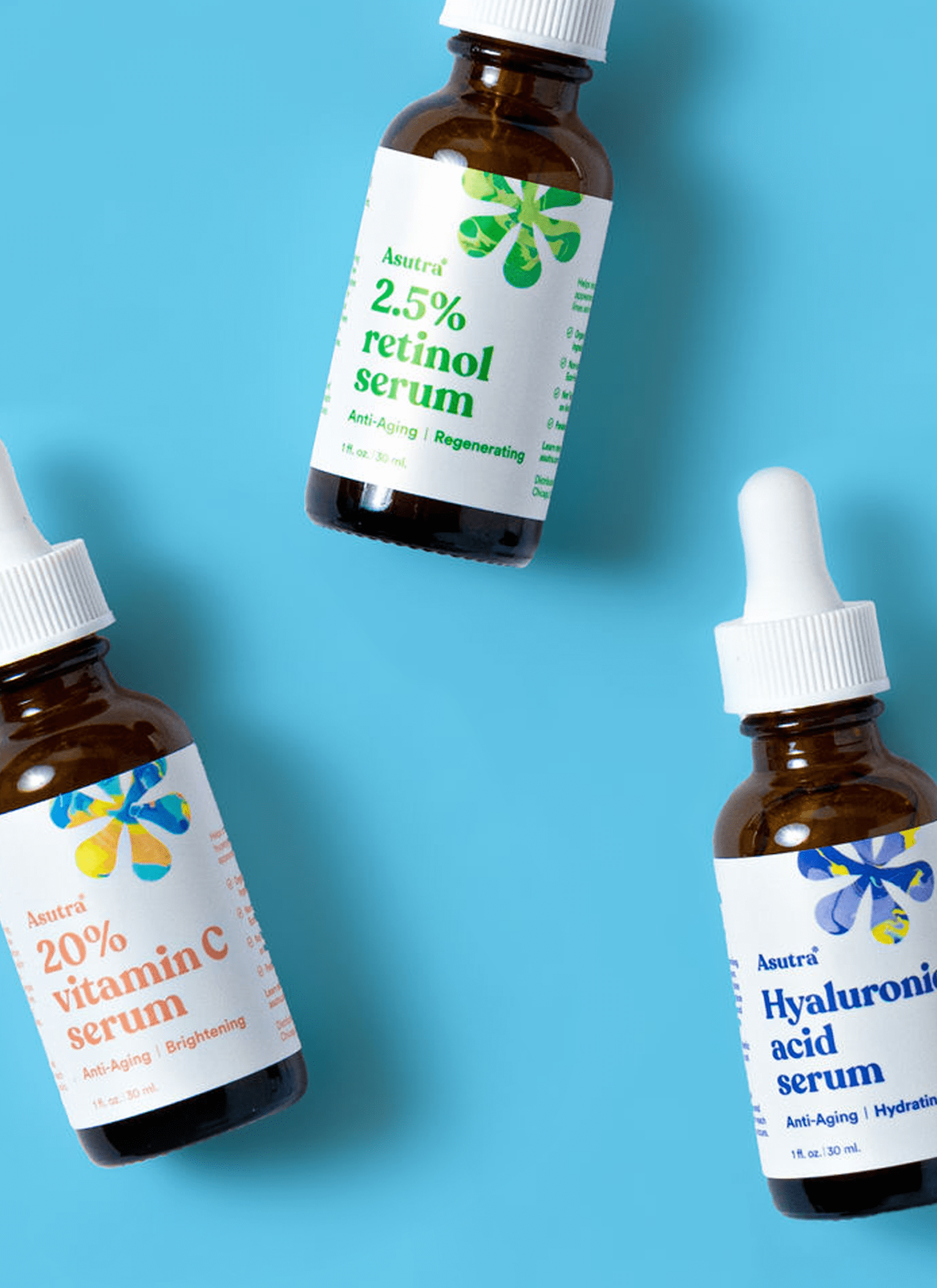 Three bottles of Asutra anti-aging serums on blue backdrop.