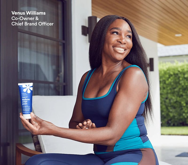 A woman in athletic wear smiling outdoors while holding a tube of magnesium menthol lotion for fast pain relief.