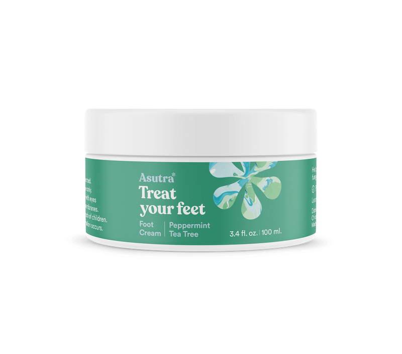 A white jar of Asutra Magnesium Foot Cream with mint and tea tree, featuring a green label with a floral design and product details.