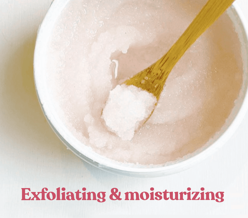 Creamy pink rose-scented body scrub with exfoliating particles and a wooden spatula, labeled "Exfoliating & moisturizing.
