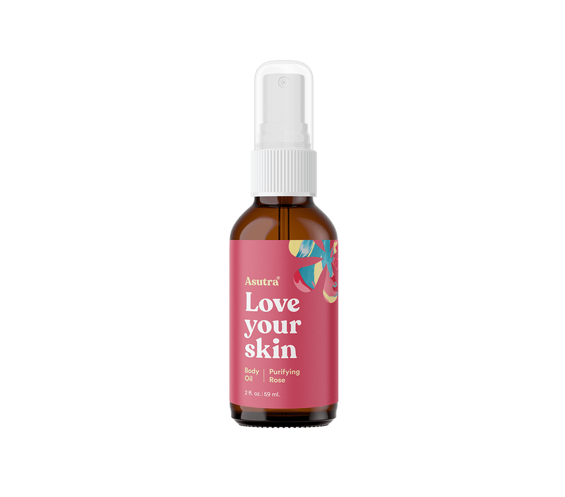 Amber glass bottle of Rose Body Oil with a spray nozzle, pink label featuring floral design, and text "Love your skin" and "Purifying Rose.