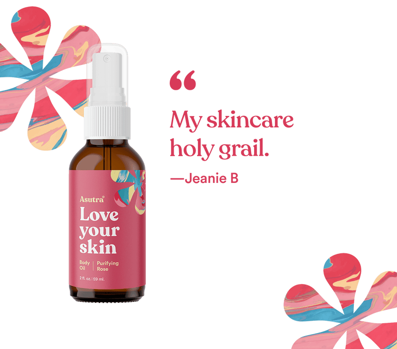 Amber glass spray bottle of rose-scented body oil with pink label, floral design, and white spray nozzle, on a black background.