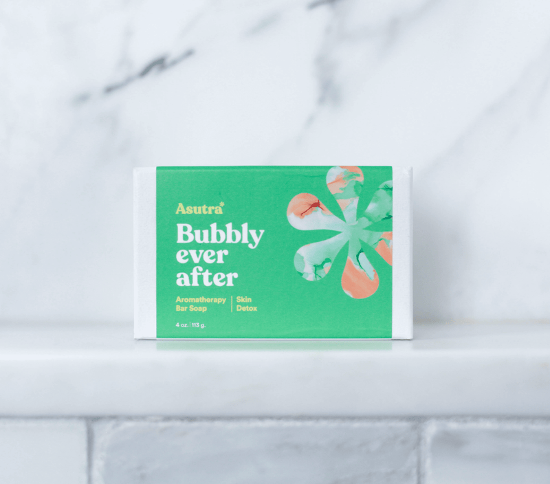 A green and white bar soap packaging labeled "Asutra Bubbly Ever After," designed for aromatherapy and skin detox, on a white surface.