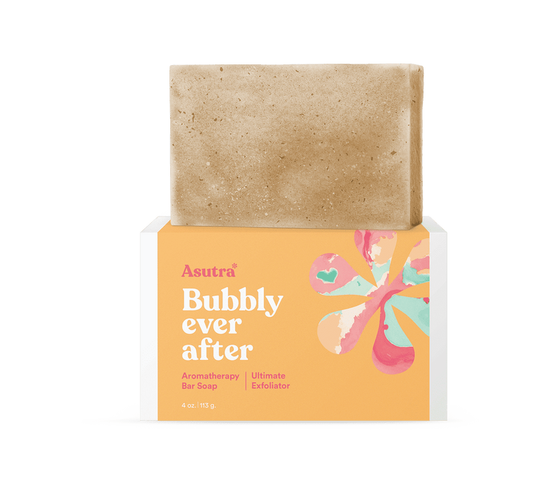 A beige exfoliating bar soap resting on a colorful box labeled "Bubbly ever after" with pink, blue, and peach abstract floral design.