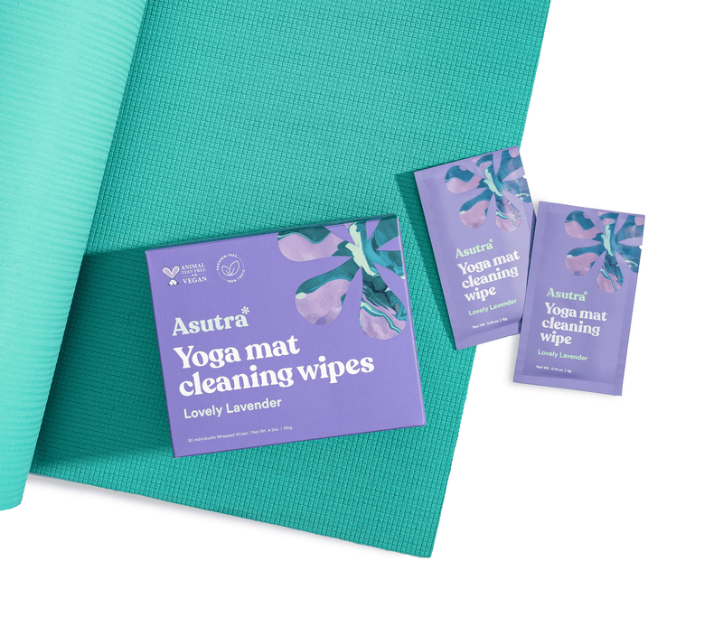 Lavender-scented yoga mat cleaning wipes sachets on teal yoga mats, featuring purple packaging with floral design and product info.