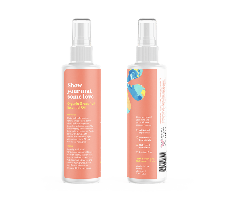 Bottle of Calming Citrus Yoga Mat Cleaner with a spray nozzle, featuring a peach-colored label and abstract blue and yellow design.