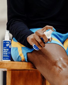 A person sprays Asutra Spray Pain Away Magnesium Oil on their knee. 